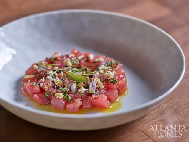 Tuna tartare with herbs, capers, and dressing in a white bowl.