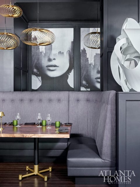 Dining booth with gray tufted upholstery, dark wood table, and modern pendant lights.