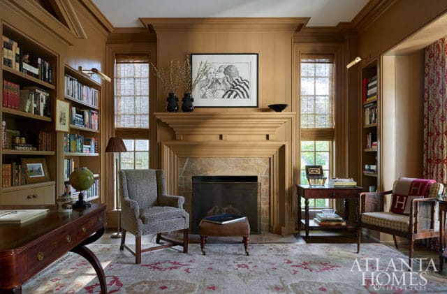 Library with tan walls, built-in bookshelves, fireplace, and patterned chairs.