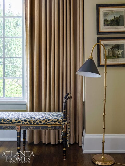 Bench with blue and gold patterned upholstery next to gold bamboo floor lamp.