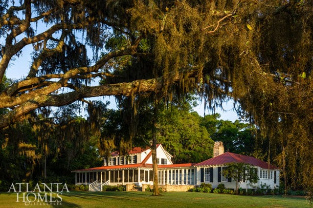 White house with red roof, screened porch, and large oak tree with Spanish moss