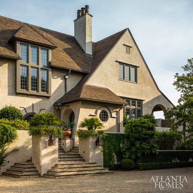 Tudor-style home with stucco exterior, arched entryway, and stone steps.