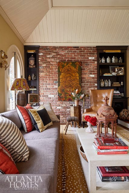 Living room with gray sofa, brick fireplace, leather chair, and tiger artwork.