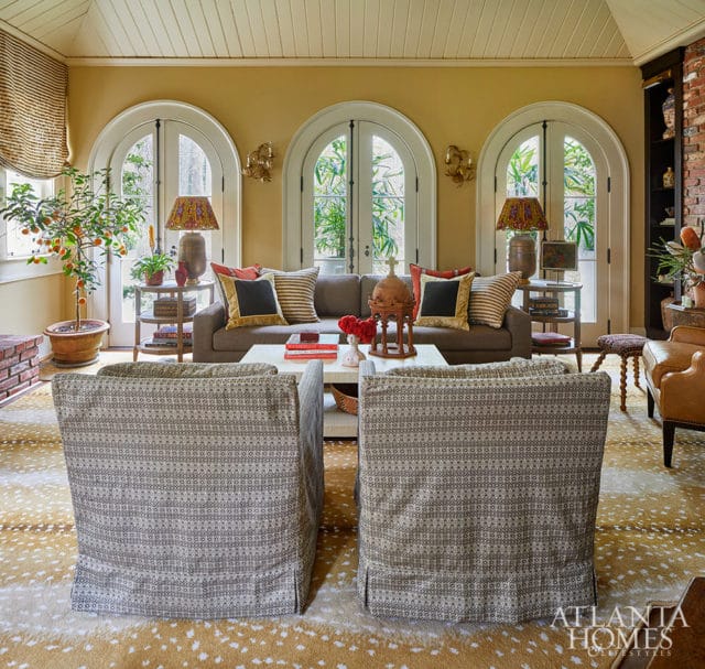 Family room with yellow walls, arched doors, patterned chairs, and a deer hide rug.