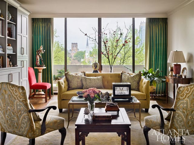 Yellow tufted sofa with patterned pillows, flanked by ornate chairs.
