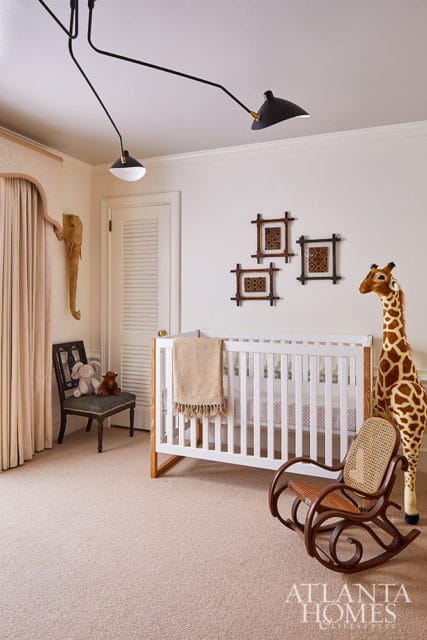 Nursery with white crib, rocking chair, stuffed giraffe, and elephant wall decor.