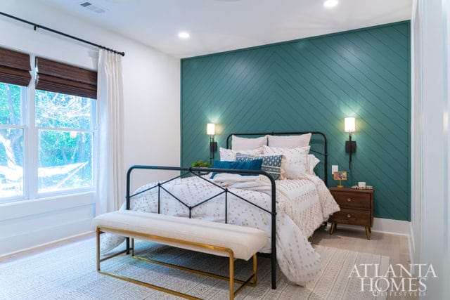 Bedroom with teal chevron accent wall, black metal bed, and white bedding.