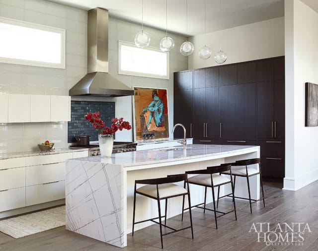 Modern kitchen with white cabinets, marble island, dark wood cabinets, and stainless steel range