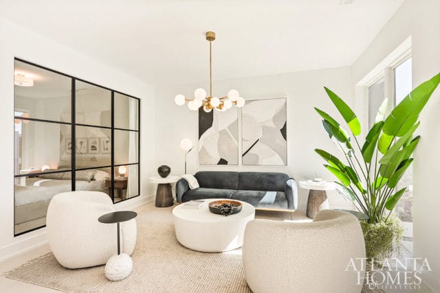 Living room with white boucle chairs, gray sofa, white coffee table, and abstract art.