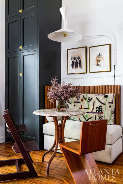 Dark gray built-in cabinets, marble-top table, and upholstered bench with graphic pillows.