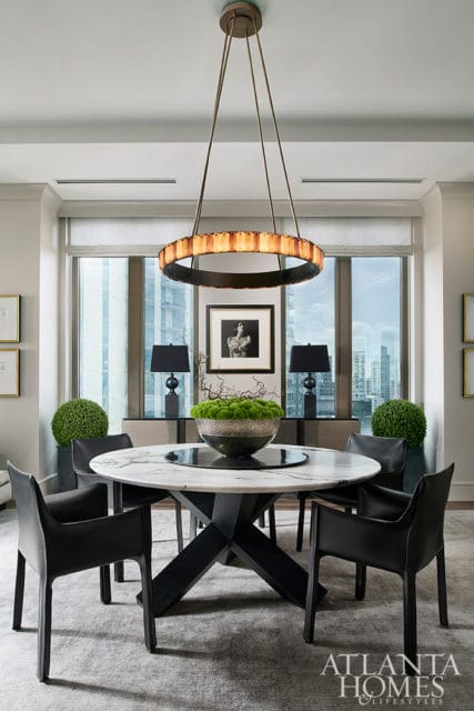 Marble dining table with black chairs, modern chandelier, and city view