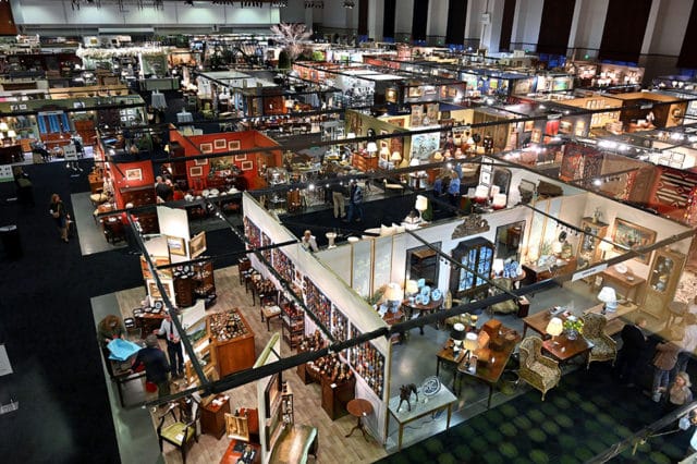 Antique furniture and decor booths with people browsing at a market
