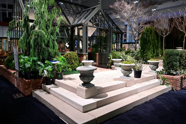 Greenhouse with stone steps, urns, and various plants.