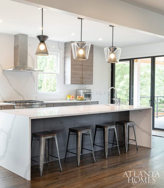 Modern kitchen with white quartz island, gray cabinetry, and pendant lights.
