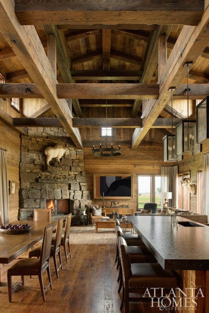 Rustic living room with stone fireplace, exposed wooden beams, and leather seating.