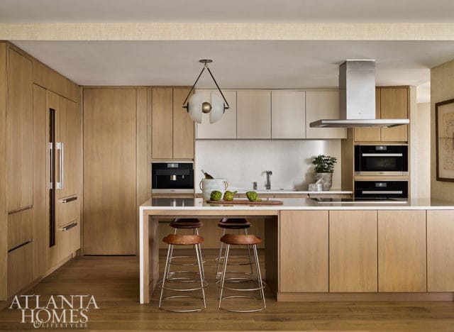 Modern kitchen with light wood cabinetry, white countertops, and stainless steel appliances. Island