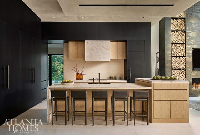 Modern kitchen with black cabinetry, wood accents, marble island, and bar stools.