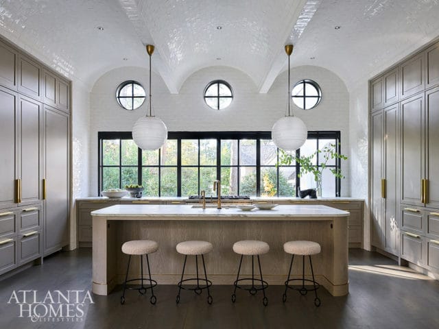 Kitchen with grey cabinetry, marble island, pendant lights, and barrel-vaulted ceiling.