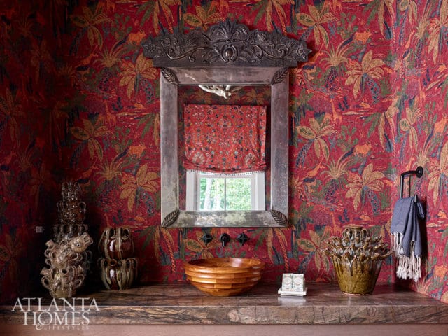 Bathroom with red tropical wallpaper, ornate mirror, wooden bowl sink, and granite countertop.