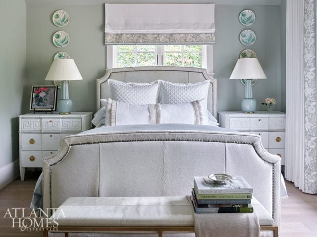 Bedroom with upholstered headboard, white bedding, and light blue lamps on nightstands.