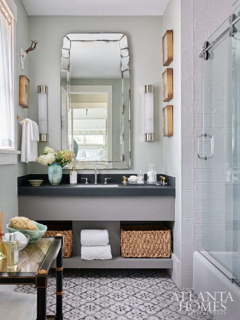 Bathroom with light green walls, a large ornate mirror, gray vanity with woven baskets, and