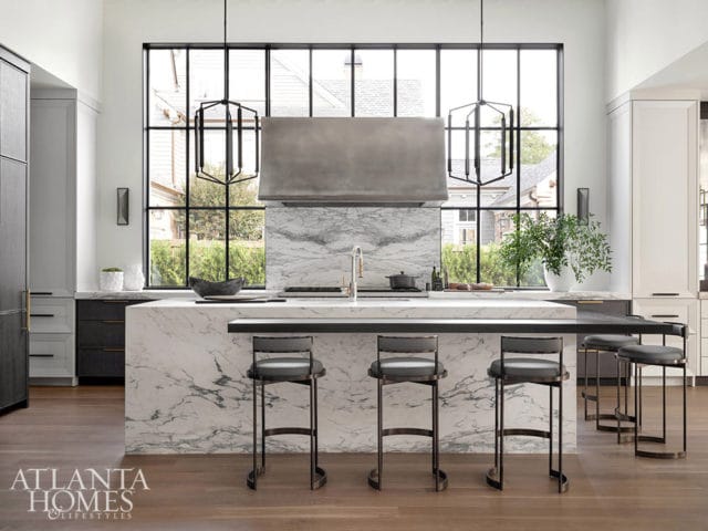 Modern kitchen with marble island, gray bar stools, and large window.
