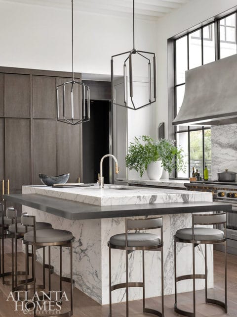 Modern kitchen island with marble waterfall edge, gray stools, and dark wood cabinetry.