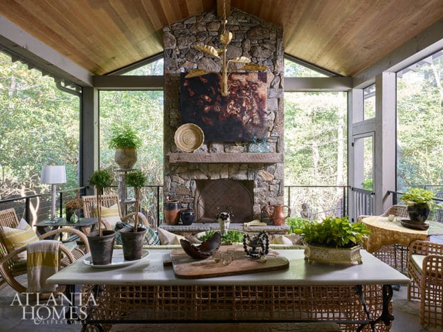 Screened porch with stone fireplace, wicker furniture, and wood-paneled ceiling.