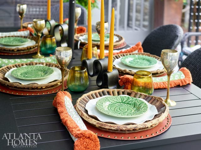 Table setting with green leaf plates, gold goblets, and orange-fringed napkins.