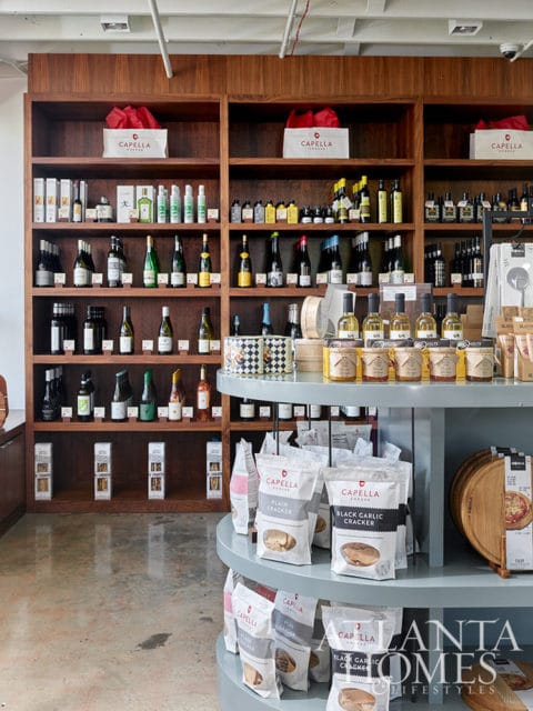 Wooden shelves stocked with bottles of wine, olive oil, and crackers. A display shelf holds bags of