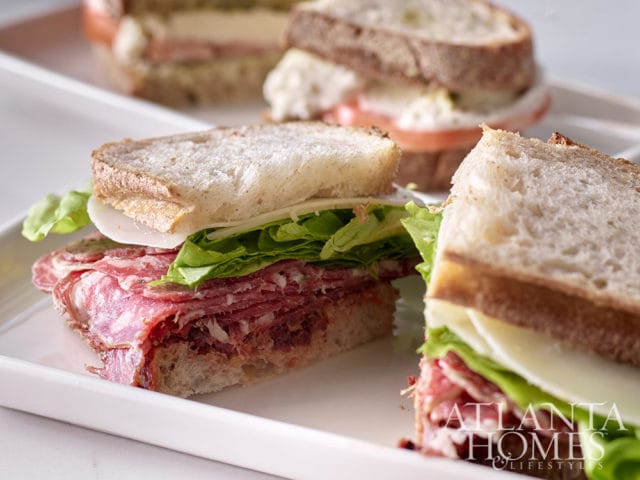 Salami sandwiches with lettuce and cheese on white platter with Atlanta Homes & Lifestyles logo