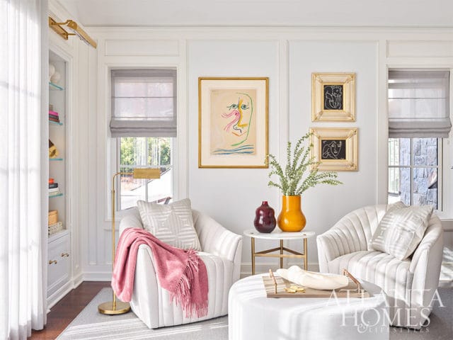 White living room with two armchairs, abstract art, and a pink throw