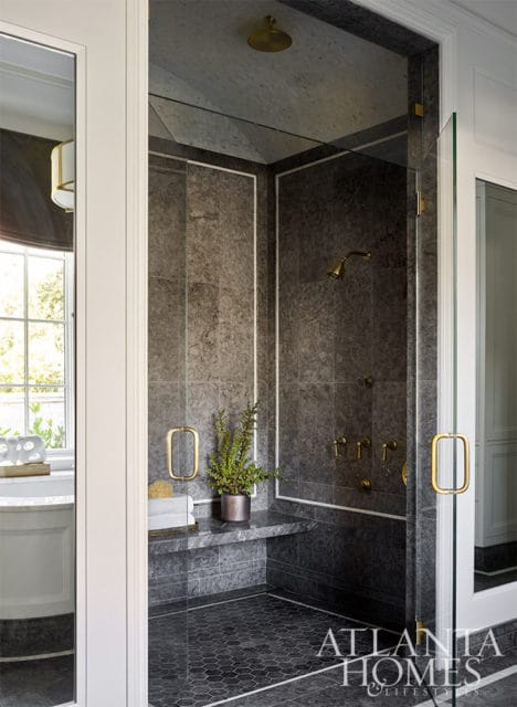 Dark gray tiled shower with brass fixtures, built-in bench, and hexagonal floor tiles.