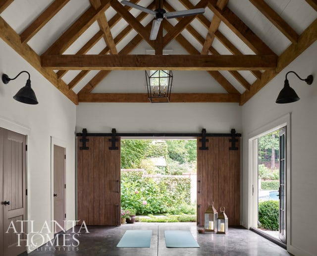 Room with exposed wooden beams, barn doors, and yoga mats