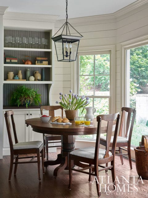 Round dining table with chairs, built-in shelving, and a lantern chandelier.