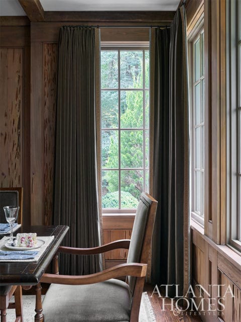 Dining room with wood paneled walls, dark wood table, and upholstered chairs.
