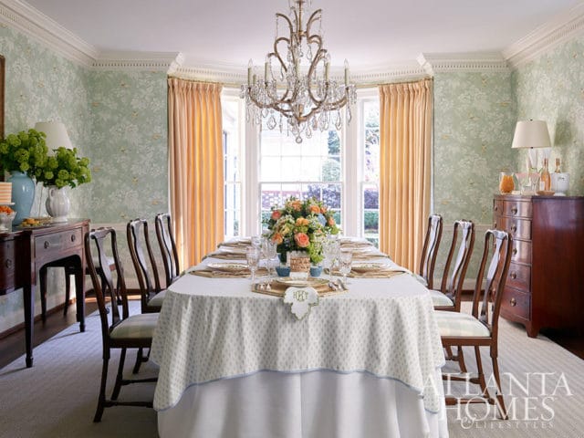 Dining room with floral wallpaper, formal table setting, crystal chandelier, and dark wood