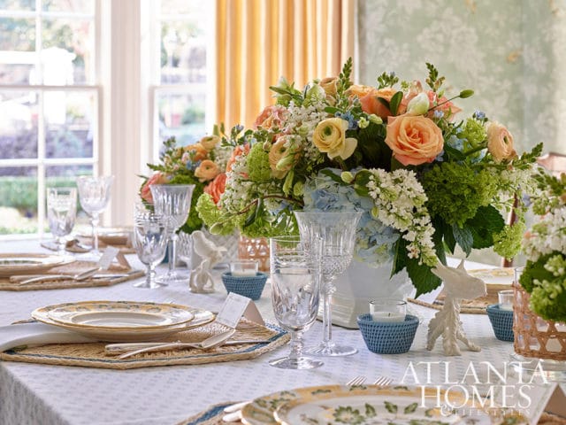 Dining table set with floral centerpiece, crystal glasses, and decorative birds.