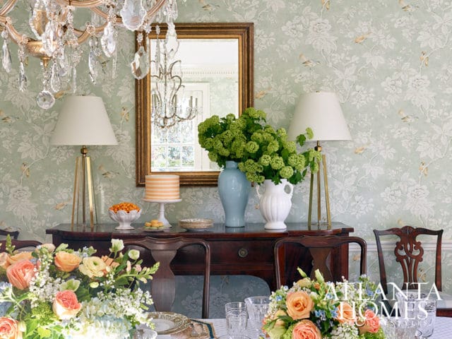 Dining room with floral wallpaper, crystal chandelier, and antique table