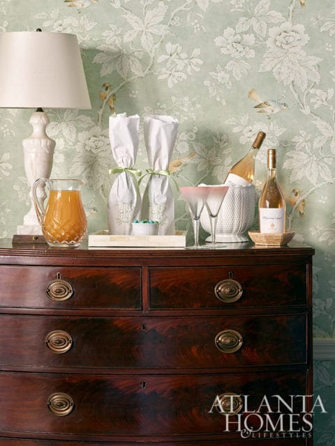 Dark wood dresser with brass hardware against light green floral wallpaper
