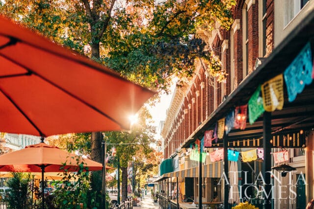 Street scene with orange umbrellas, brick buildings, and colorful flags.