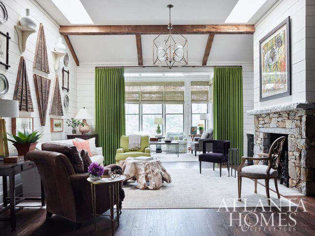 Living room with shiplap walls, exposed beams, stone fireplace, and green curtains.