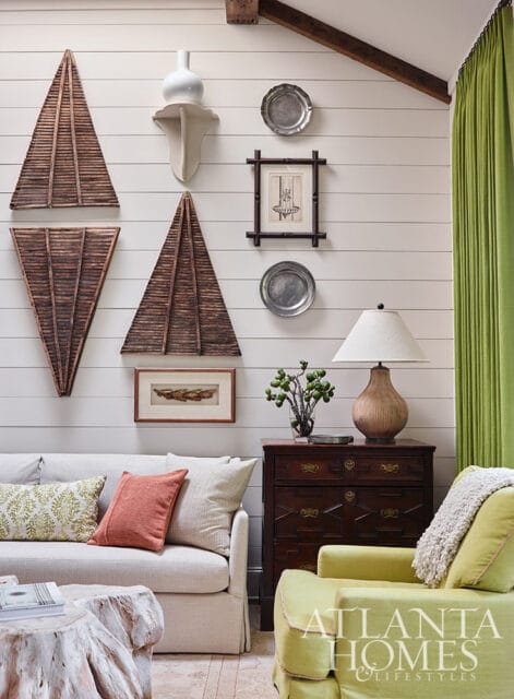 Living room with shiplap walls, textured sofa, armchair, and decorative wall art.