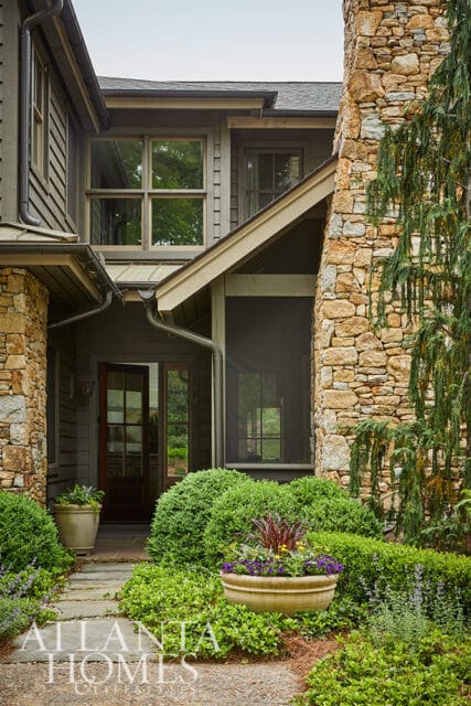 Stone and wood house exterior with screened porch and stone chimney.