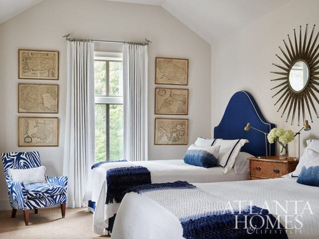 Bedroom with two twin beds, blue headboards, and framed maps on the wall.