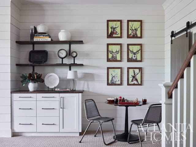 White buffet with dark wood top, open shelves, and six framed deer portraits.