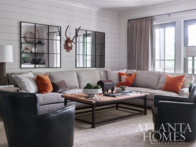 Living room with sectional sofa, leather chairs, wood coffee table, and shiplap walls.
