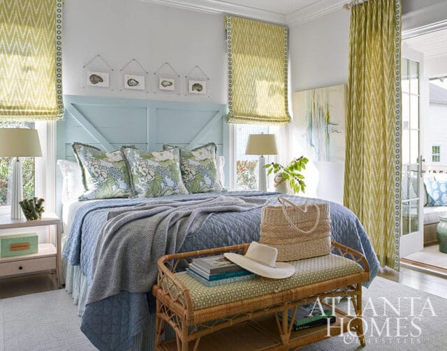 Bedroom with light blue headboard, floral pillows, and green patterned curtains.