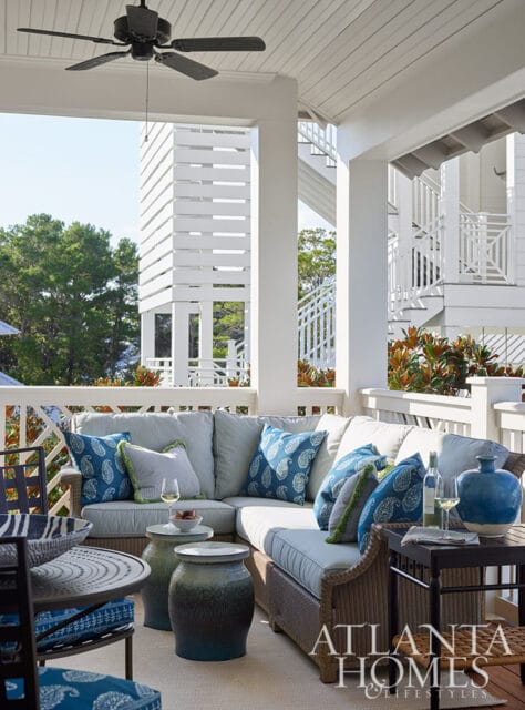 Covered porch with sectional sofa, blue paisley pillows, wicker furniture, and ceiling fan.