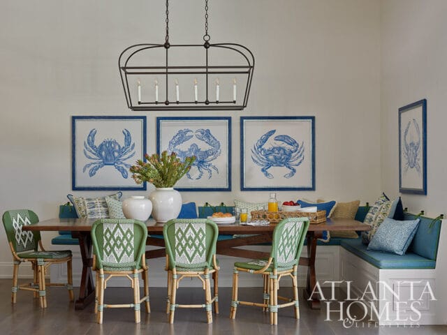 Dining room with blue crab art, green wicker chairs, and banquette seating